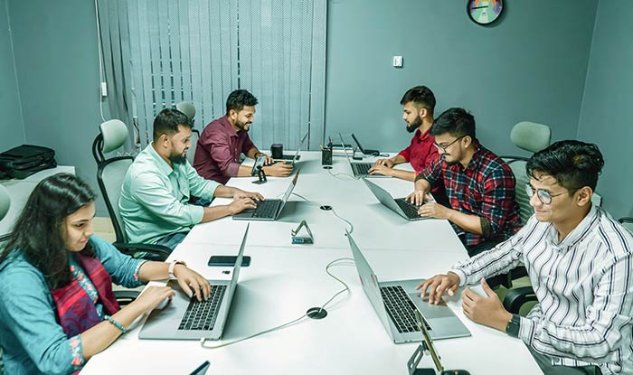 Testa engineers sitting around a table with their notebooks open, considering the software testing lifecycle